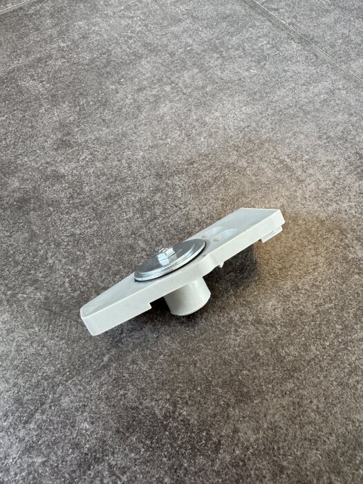 Bilden visar en reparation av en plastdel med metallskruv och mutter, lim har använts i reparationen.