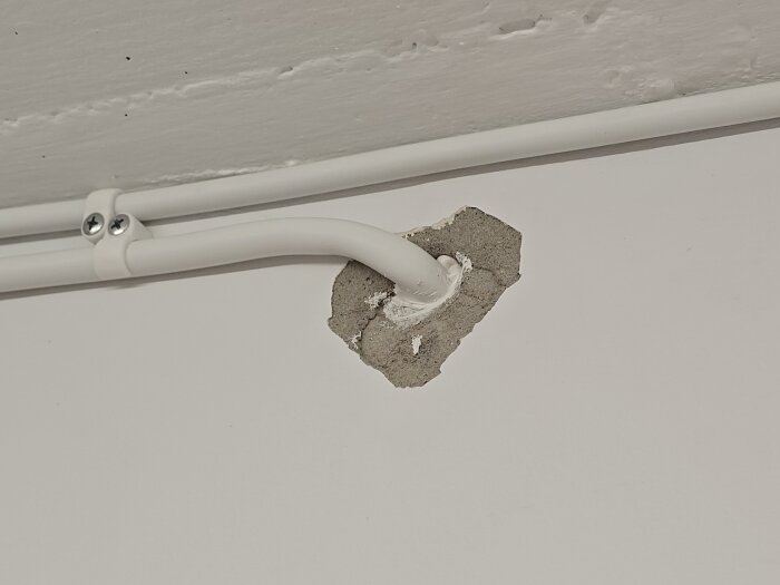 Elektrisk kabel genom yttervägg med kringliggande puts färdig för reparation efter elinstallation.