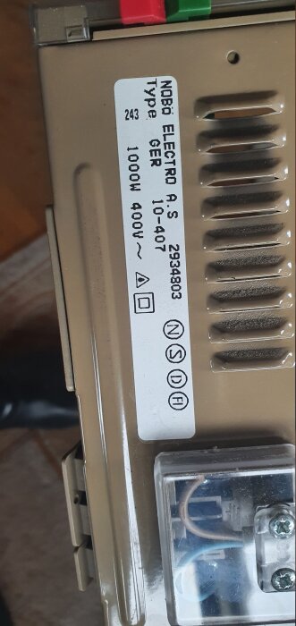 Närbild på en etikett på en elektrisk apparat från NOBØ Electro A.S, typ GER, med specifikationer som 1000W och 400V, och synliga terminaler.