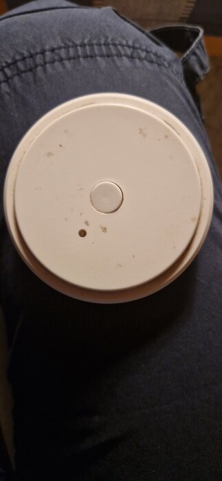 Rund vit fjärrkontroll till Ansluta belysning från Ikea, placerad på en mörk yta, synlig knapp och LED-indikator.