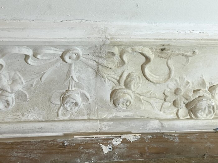 Stuckatur med blommotiv på en vägg dekorerad med gipsgjutning, delvis reparerad med ett speciallim och spackel, sett ovanifrån.