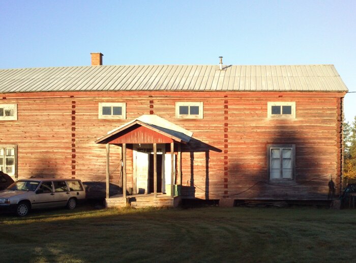 Gammalt trähemman i Norrbotten med faluröd fasad och plåttak. En bil står parkerad utanför.