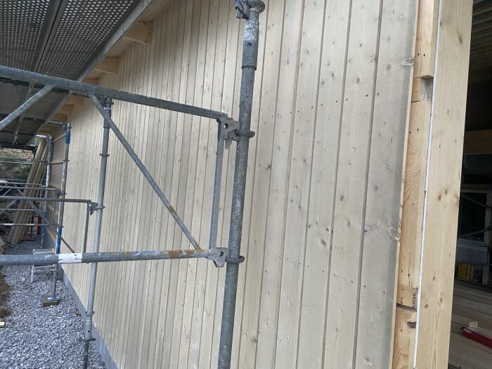 Trävägg behandlad med järnsulfat, ställning monterad framför för vidare arbete.