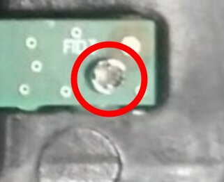 Kretskort med en rödmarkerad sektion, visar en skruv eller komponentdetalj inuti en elektrisk enhet.
