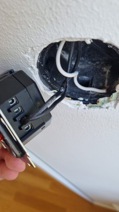 Inkopplingsdetaljer för en dimmer med kablar i en väggenhet, sett från sidan.