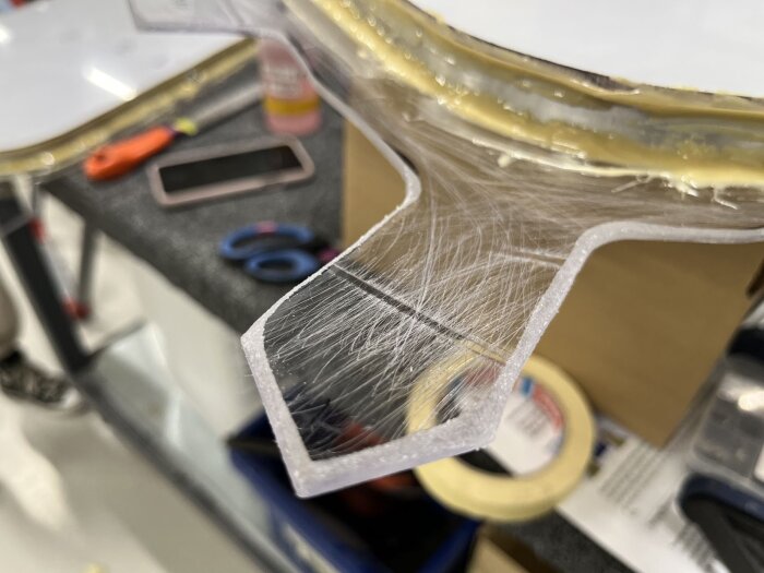 Glasfiberskyddad och sandpapprad kant av del av fönster, redo för montering i husvagn, med verktyg och material i bakgrunden.