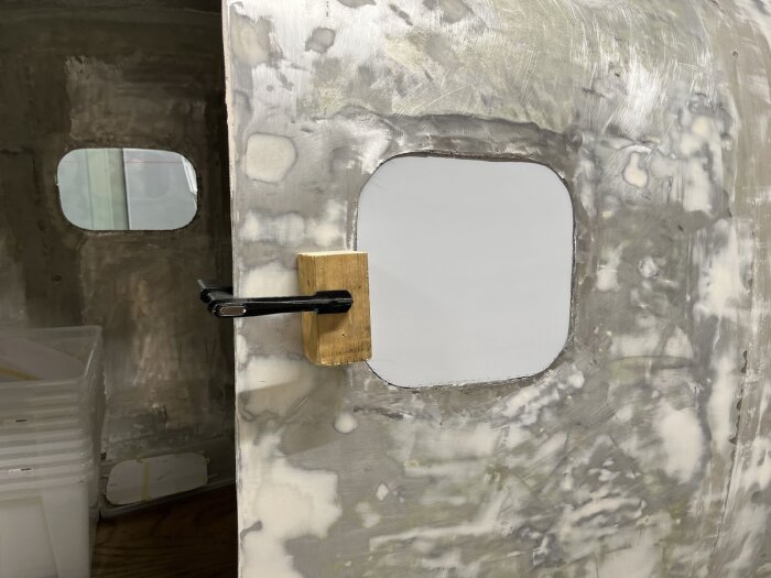 Montering av fönster i en husvagnsvägg, med fönstret fastspänt och ytan omkring slipad och förberedd för installation.