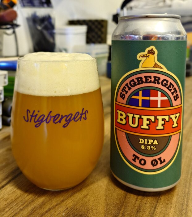 En burk Stigbergets Buffy DIPA 8.3% och ett glas med öl står på ett bord.