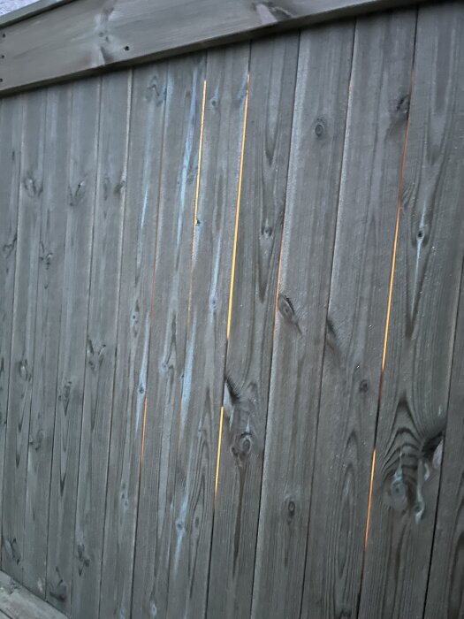 Träplank med springor genom vilka ljus syns från belysningen bakom, en del av ett byggprojekt där ljus- och bländningsproblem diskuteras.