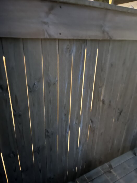 Träplank med ljus som lyser igenom springorna från en lampa.