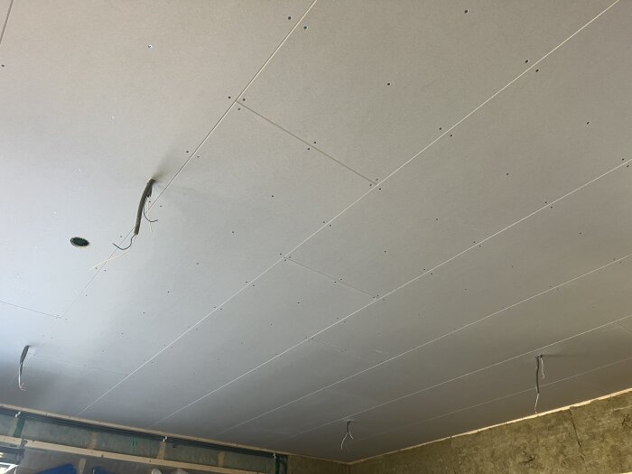 Gipstak med fastsatta gipsskivor och synliga elkablar som hänger ner, del av renoveringsprojekt.