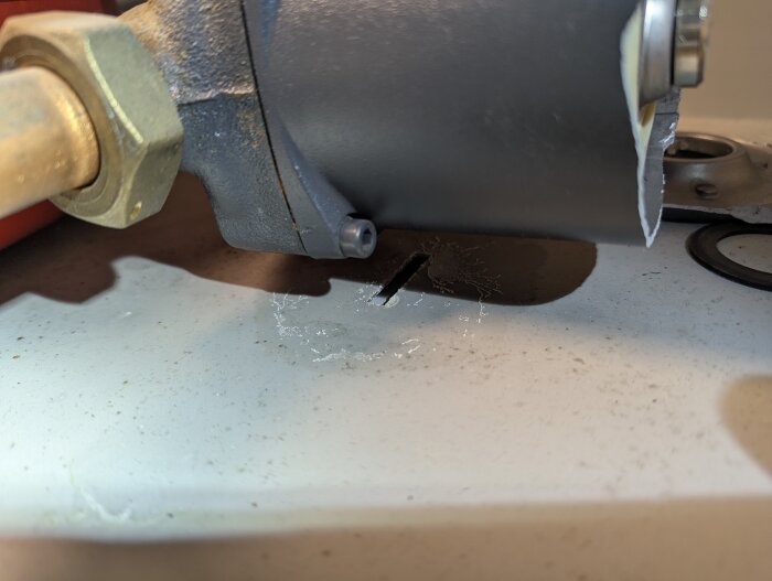 Cirkulationspump med möjlig läcka, papper under för att upptäcka droppar, fokus på koppling och pumpens framsida.