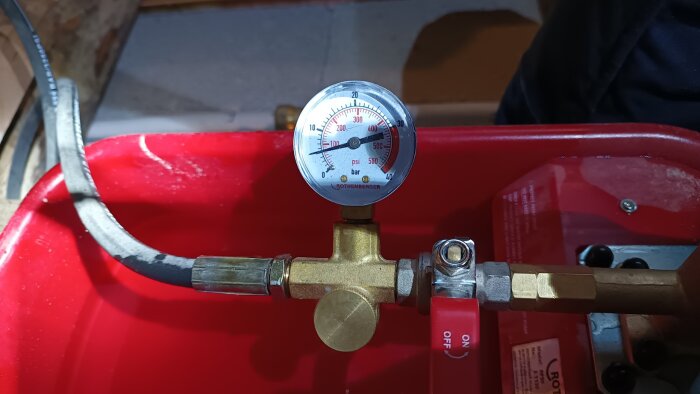 Tryckmätare visar 5 bar, monterad på röd testapparat för tryckkontroll vid rörinstallation.