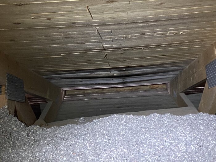 Råspont med mörka fläckar synliga ovan en altan, isolering med lösull (cellulosa) i förgrunden. Ventilation kan vara otillräcklig.