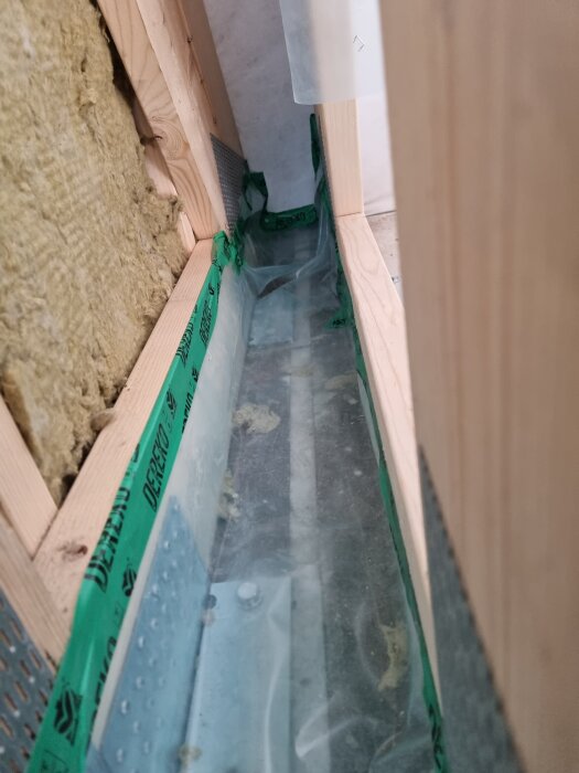 Plastad och regelbyggd vägg med isolering och byggplast inuti träkonstruktionen.
