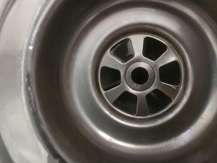 Köksdiskho i rostfritt stål med avloppssilen synlig. Packningen ser ut att sticka upp något runt kanten.