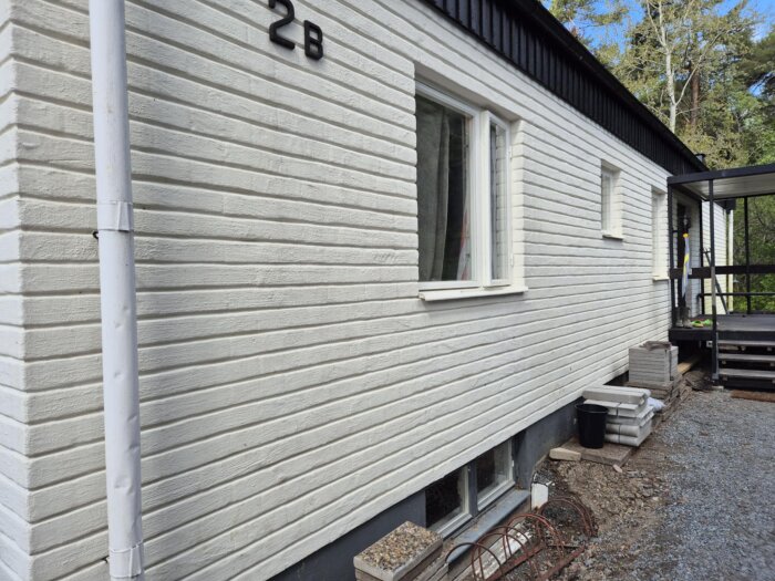 Vitmålad husfasad med rena tegelväggar, synlig efter fasadtvätt.