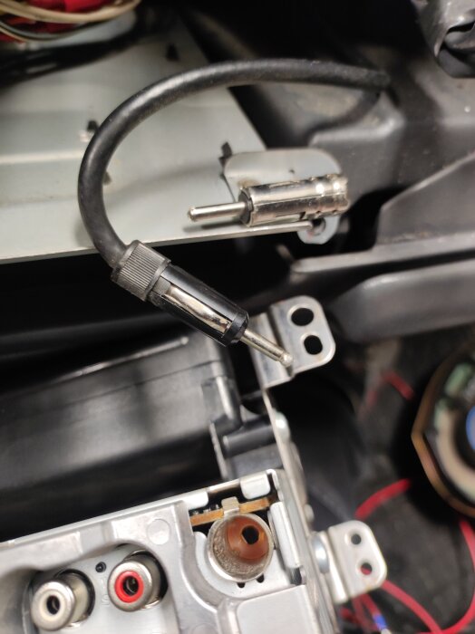 Antennadapter monterad i en bilstereo, visar anslutna kablar och metallkomponenter.