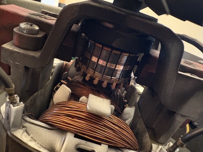 En nära bild av en motor med koppartrådar och kolborstar, del från en Husky Q-extra, visas öppen för inspektion av skicket på kolen.