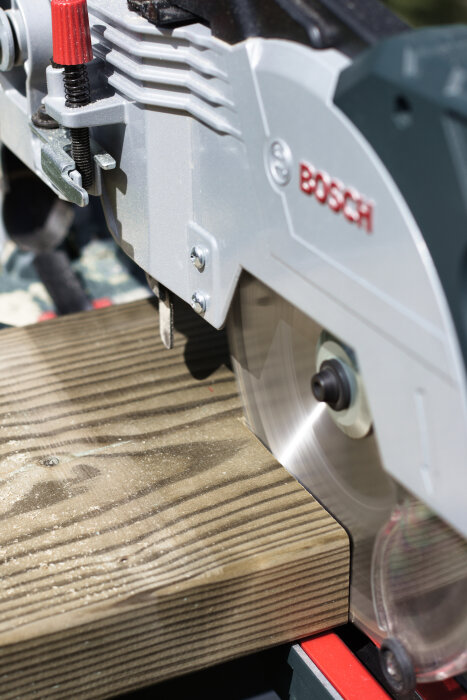 Kap- och gersåg från Bosch skär en trärege i bygge av odlingslåda, med fokus på klingan i arbete.