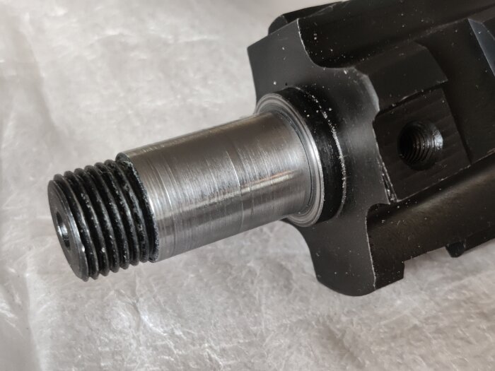 Metallspindel med gängad ände och bearbetad yta som visar svarvning och slipning, del av ett maskinprojekt för att passa en lageraxel på 17 mm.