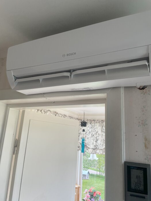 Bosch air-to-air heat pump mounted above an interior doorway, part of a home's heating system discussion.