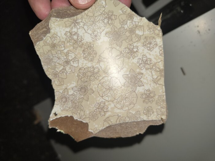 Skiva med blommönster, möjlig fuktskydd, misstänks innehålla asbest, från ett hus byggt 1975, fotograferad i tvättstugan.