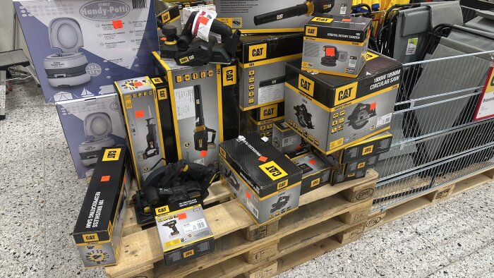 CAT-verktyg och två största kartonger på pall med rabatterade prislappar på Jula Värmdö, omgivet av andra lagerförda produkter.