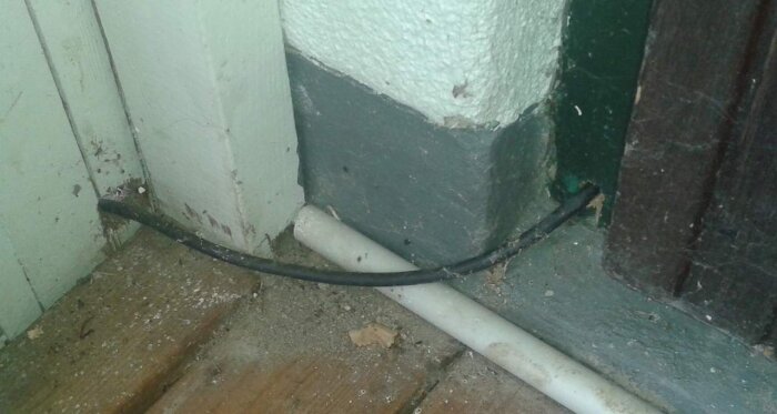 Slarvig kabelinstallation vid vägg och golv med exponerade ledningar.