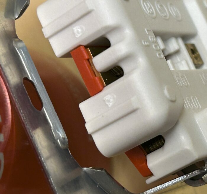 Elektriskt vägguttag av hög kvalitet med vit plast och metallfäste.