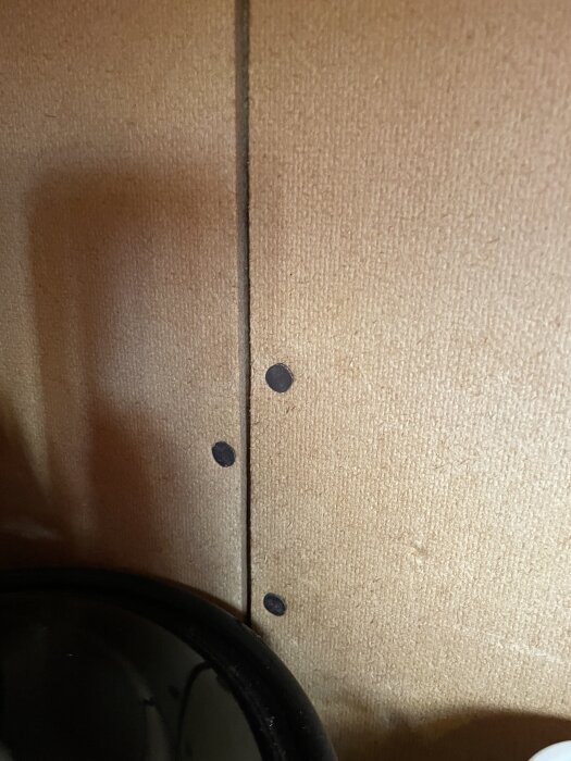 Bild på närbild av ett köksskåp från 1939, fastsatt med spikar i en vägg, detaljer av trä och skuggor synliga.