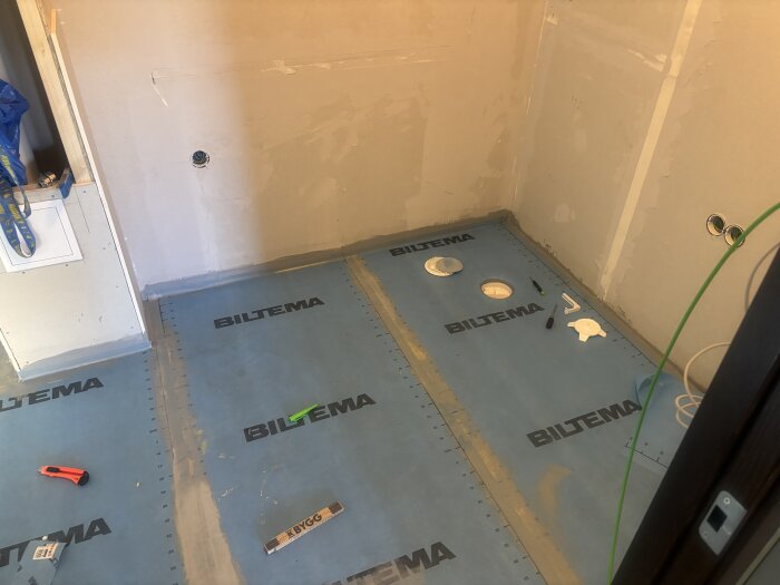 Tätskikt från Biltema installerat på golv med verktyg runtom; rum förbereds för klinkerläggning.