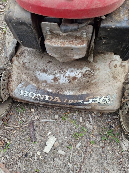 Smutsig Honda HRS536 gräsklippare fotograferad ovanifrån med synligt klistermärke och rostig motor.