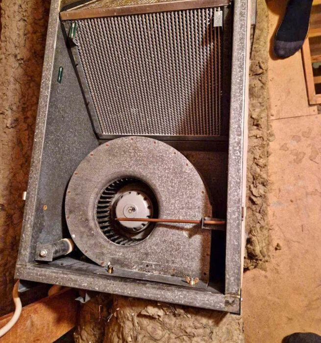 Fläkt inuti ett ventilationssystem, synlig motor och hölje; används i diskussion om byte och reparation.