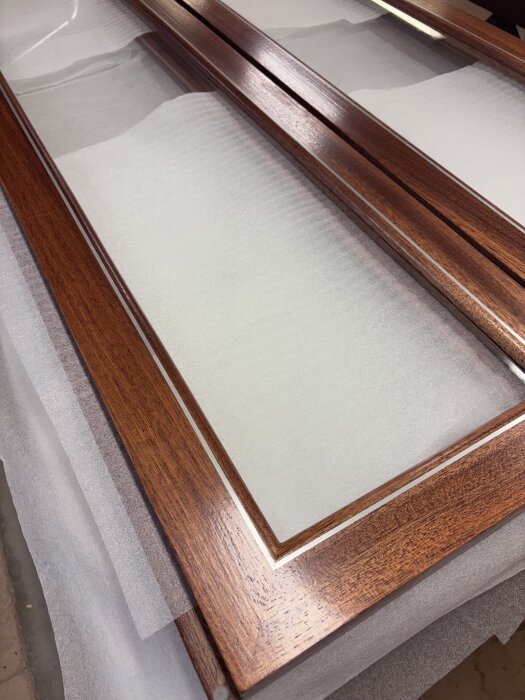 Glasade träluckor med tydliga trädetaljer, placerade på skyddande underlag.