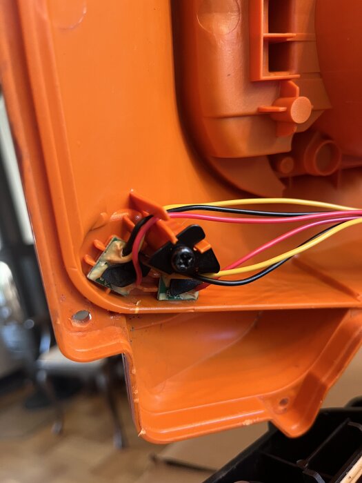 Två små magneter och kretskort på insidan av det orangea skalet till en Worx Landroid WG790, med synliga kablar.