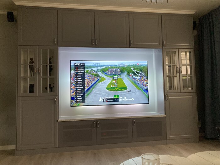TV inbyggd i hyllsystem visar en Formel 1-tävling.