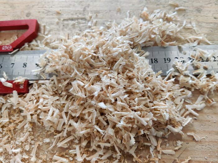 Trähögar och en linjal som mäter spånens längd efter en planhyvels installation.