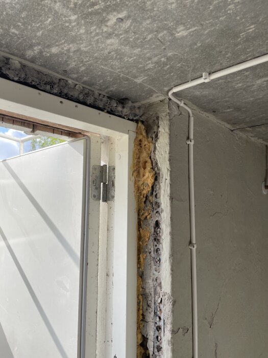 Basement doorway with exposed stone and insulation, showing unfinished construction near entrance. Wiring is visible, highlighting renovation needs.