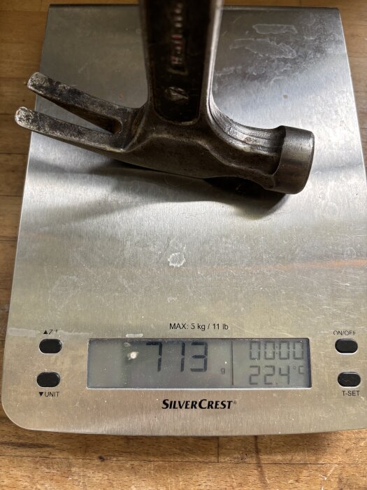 Vikt av en hammare på en köksvåg visas som 713 gram, med display som visar även temperatur, 22.4°C.
