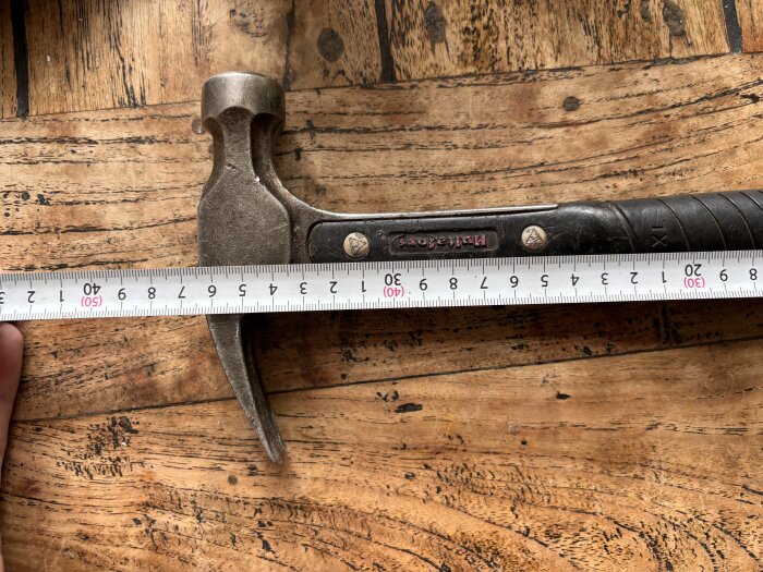 Hammare med måttband på träbord, visar längd mot enheten TR16.