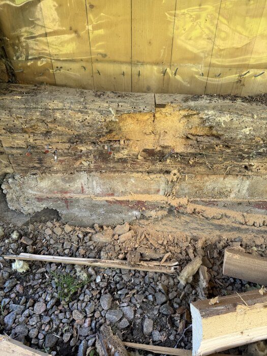 Röten rakennuksen alapuu, jossa näkyy syöpymiä ja vaurioita ulkoseinän alaosassa.