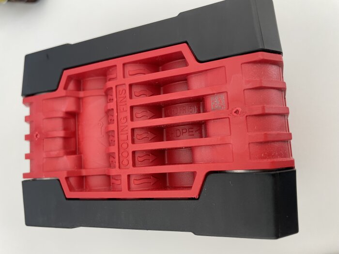 Rött och svart batteripack märkta "COOLING FINS", potentiellt ej original, med tecken på dålig passform.