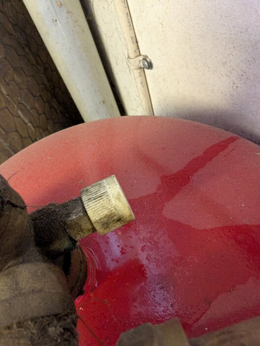 Rött expansionskärl med två ventiler; den ena ventilen läcker vatten medan den andra släpper ut luft.