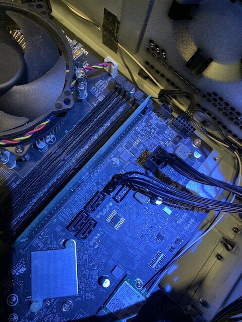 Datorn invändigt med synliga moderkort, kablar och fläkt. ATX-kontakter upptagna.