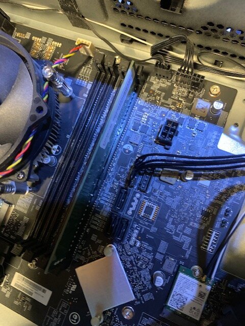 Datorens moderkort med kopplade strömkablar, CPU-kylfläns och RAM i slots. Kablaget från ATX-strömkontakten synligt.