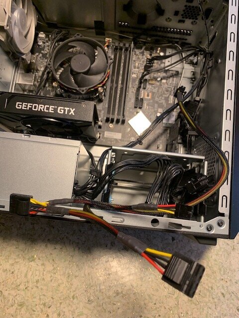 Datorchassi med öppet sidolock visar moderkort med grafikkort från GeForce och kablar anslutna från nätaggregatet. En ATX-kabel är i fokus.