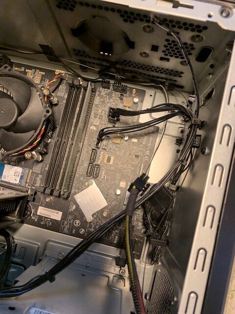 Dators inre med moderkort, fläkt och kablar synliga, inklusive ockuperade ATX-slots. Inget utrymme för extra hårddiskanslutning.