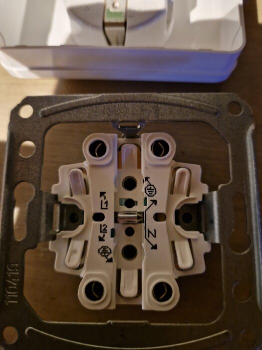 Eluttagets insida med kopplingsdiagram och anslutningspunkter, monterad på en metallram, i närbild.