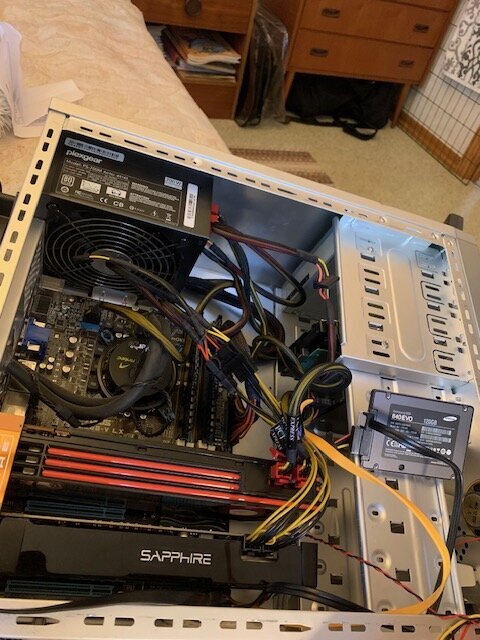 Öppen datorkomponent med kablar och kretskort synliga, märket Sapphire på grafikkortet.